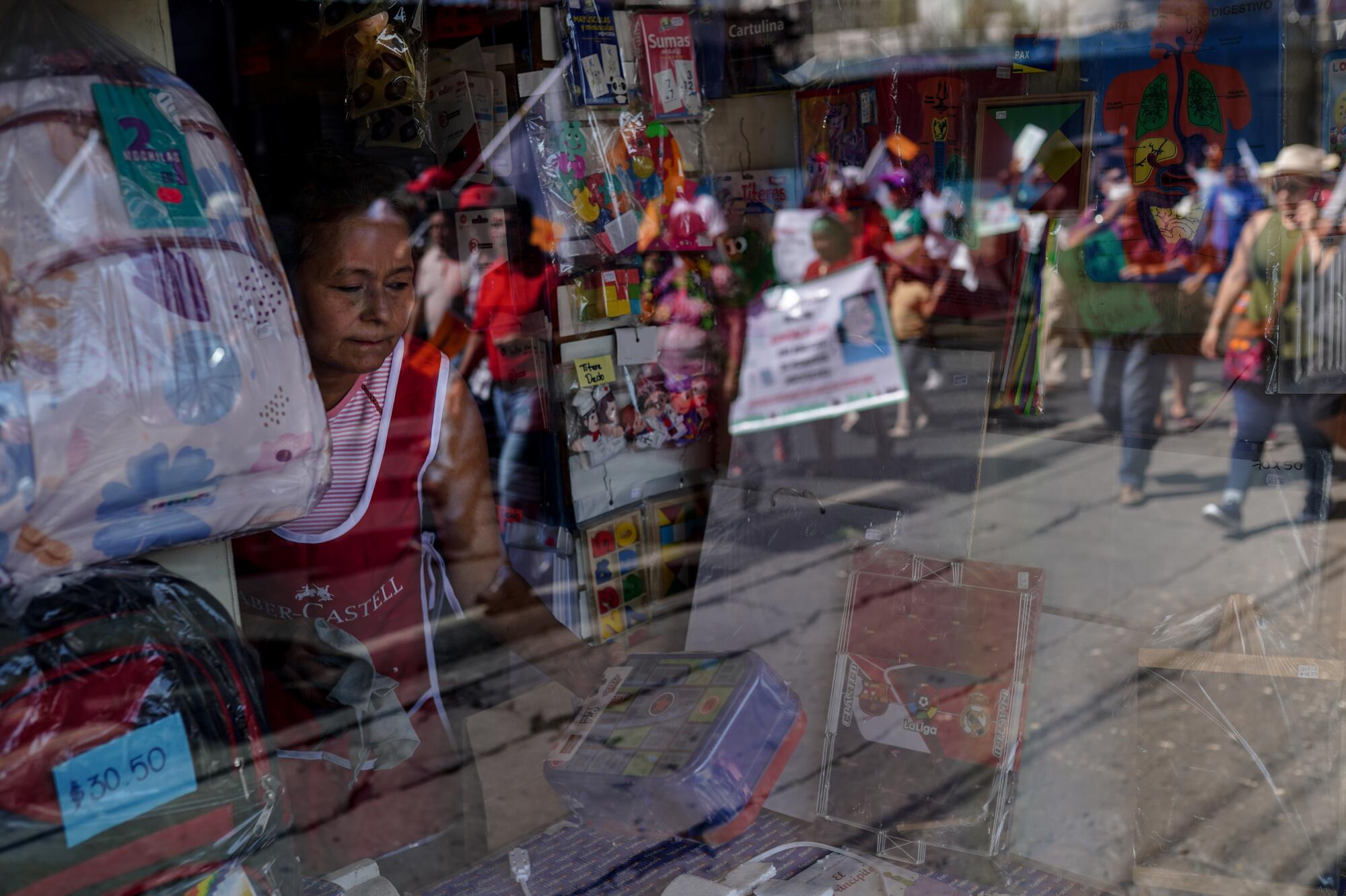 A woman stacks a shelf as demonstrators march to protest