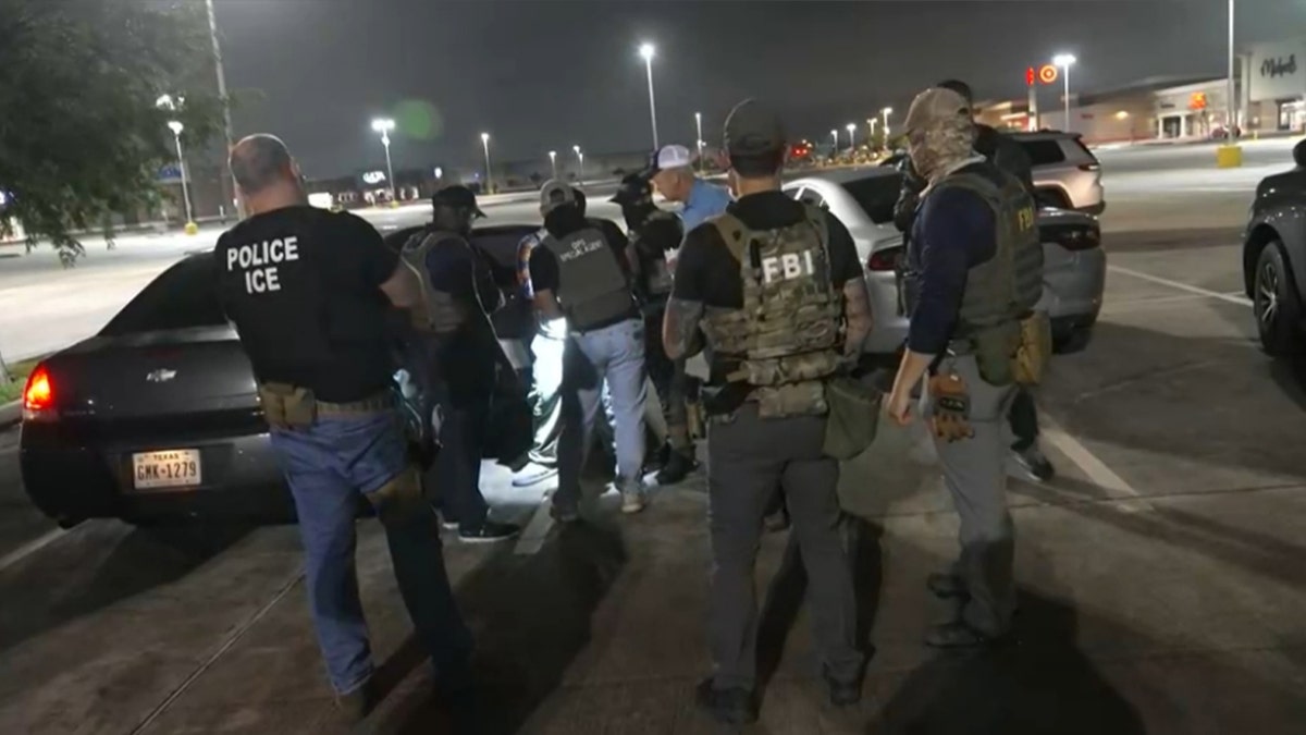 many police officials crowd car as they detain a man