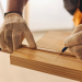 Carpenter measuring and cutting a wood plank