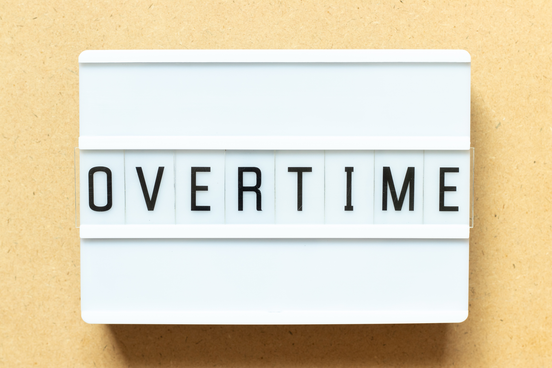 white sign that says "overtime" on beige background