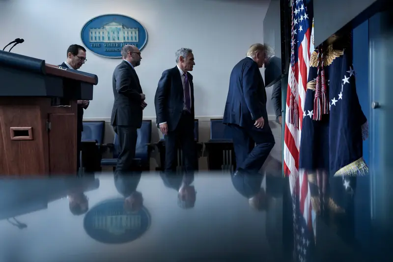 Vought walks behind Trump with other men in suits leaving a room in the White House.