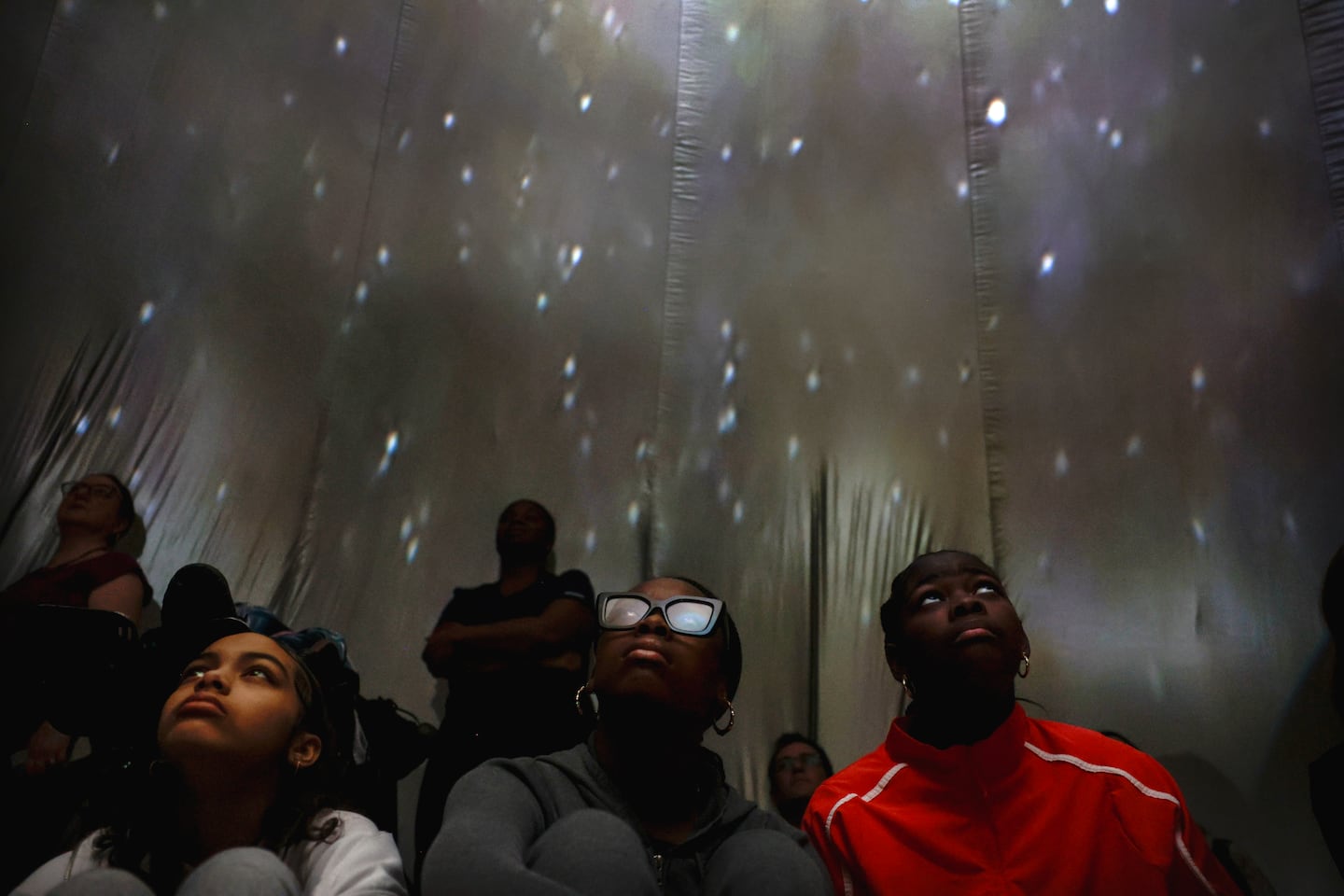 Seventh-graders Jaziah Sylvert, Donnay Burton, and Arianna Lang took in the scene inside a mobile planetarium at the school gymnasium on Dec. 11, 2024. 