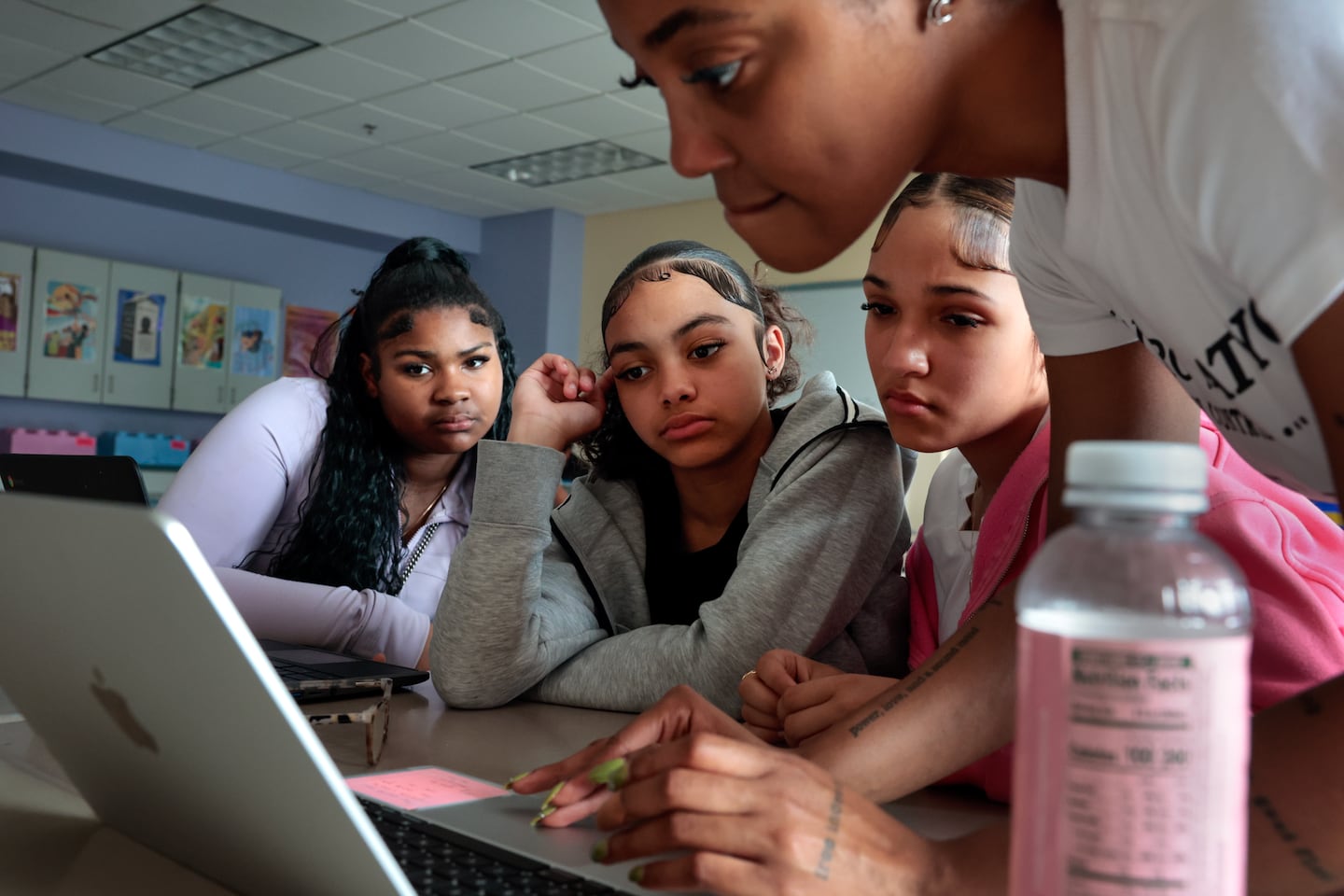 Seventh-graders Honesty Graham, Aaliyah Figueroa, and Jaylani Latorre researched a social studies project with teacher Taylor Roberts (right) on June 4. The students were working on a presentation about immigration and were watching a news report regarding Rümeysa Öztürk, the Tufts PhD student detained by immigration authorities. 