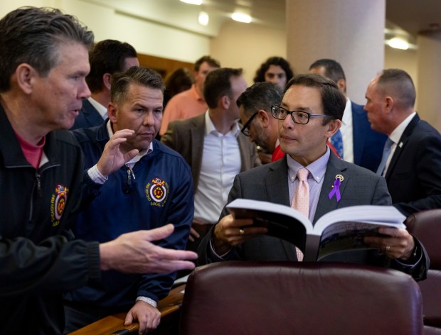 Ald. Raymond Lopez, 15th, looks at the proposed budget with Patrick Cleary, left, and Eric Steinmetz, president and vice president of Chicago Fire Fighters Union Local 2 on Oct. 16, 2025, in City Council chambers after Mayor Brandon Johnson delivered his budget address at Chicago City Hall. (Brian Cassella/Chicago Tribune)
