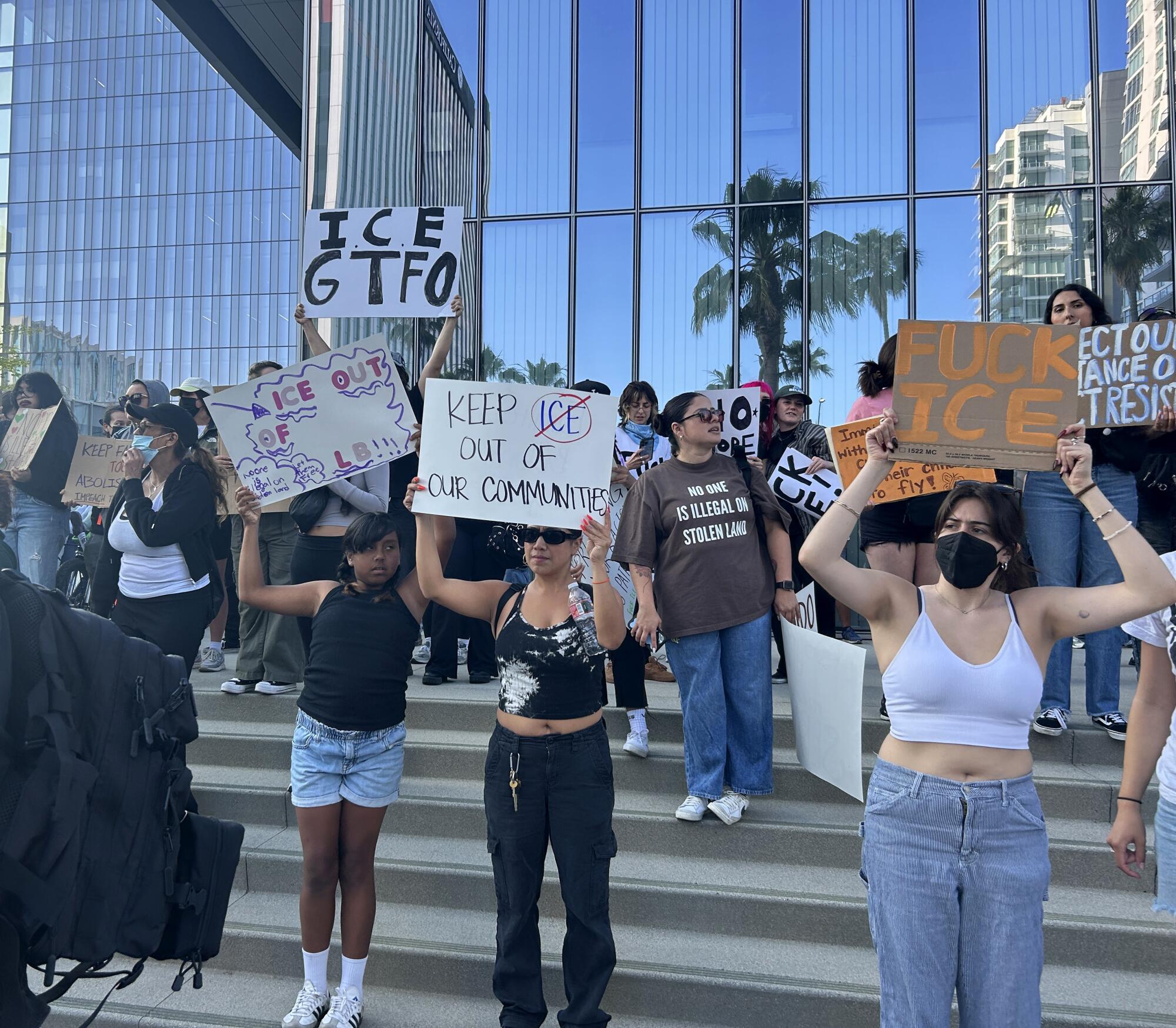Demonstrators hold signs outside of Long Beach Civic Center on Tuesday.