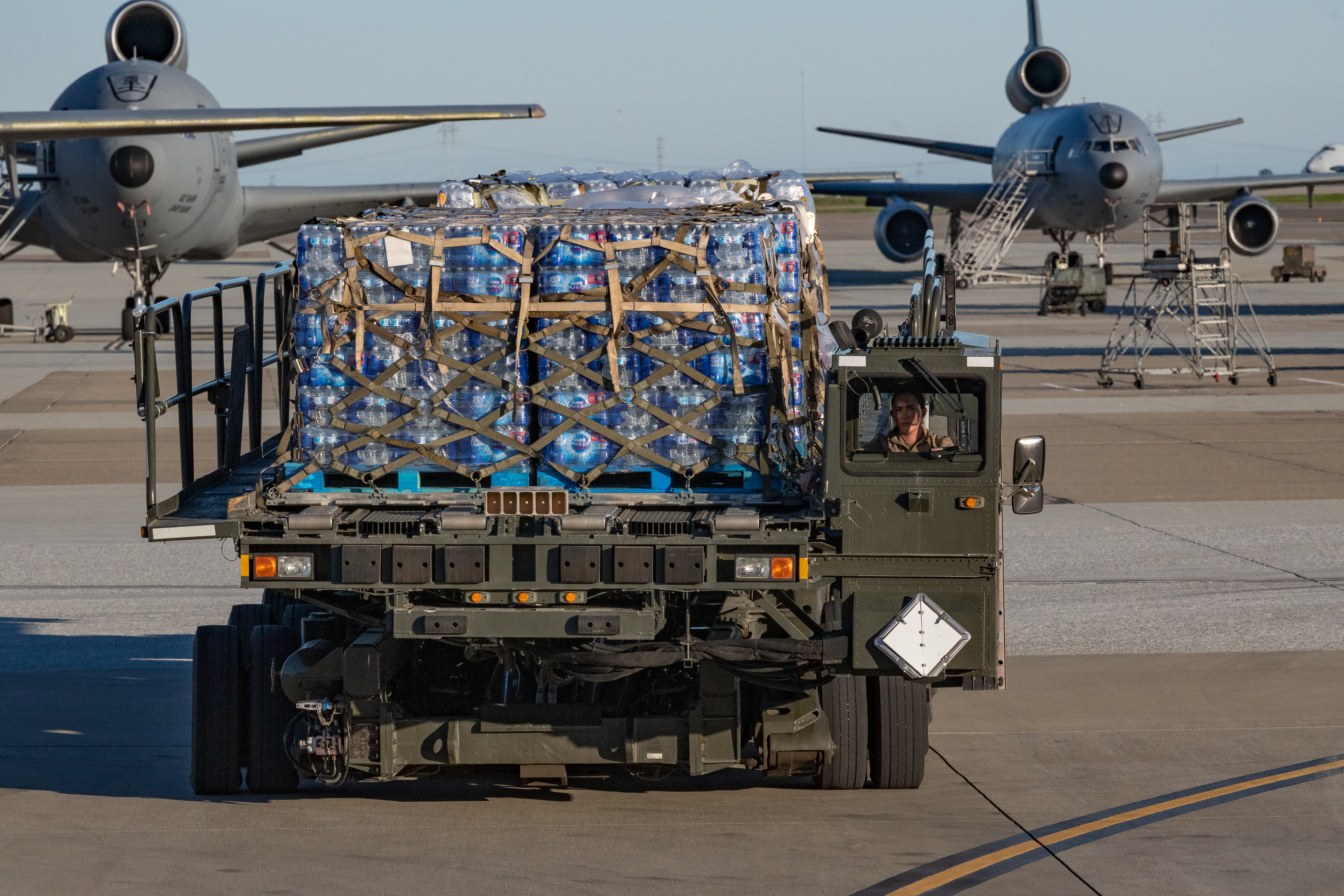 Air transportation specialists from the 60th Aerial Port Squadron at Travis Air Force Base, California assist in loading water and other supplies onto a U.S. Air Force C-17 Globemaster III from the 446th Airlift Wing, Dec. 10, 2021. The Joint Base Lewis-McChord C-17 stopped at Travis, while en route to support the U.S. Transportation Command (USTRANSCOM) Red Hill Water Movement for Joint Base Pearl Harbor-Hickam, Hawaii, water quality restoration efforts. They delivered more than 52,000 half-liter bottles of water to help military members and their families. (U.S. Air Force photo by Grant Okubo)