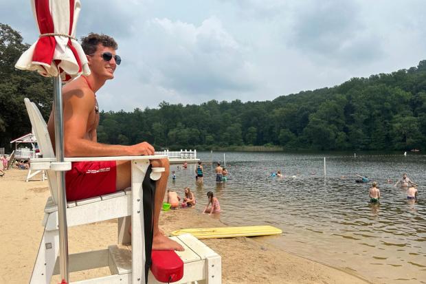 Lifeguard Luke Macchione watches over swimmers and boaters Wednesday, Aug. 6, 2025, on Lake Conewago in Mount Gretna, Pa., a town that springs to life every summer, when its picturesque front porches become filled with energetic cottagers. (AP Photo/Mark Scolforo)
