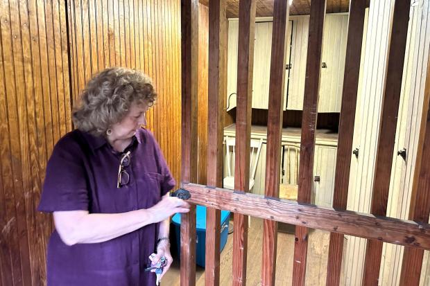 Local historian Sue Hostetter opens the door to the rarely used jail cell with wooden bars on the second floor of the Hall of Philosophy, Wednesday, Aug. 6, 2025, in Mount Gretna, Pa. (AP Photo/Mark Scolforo)