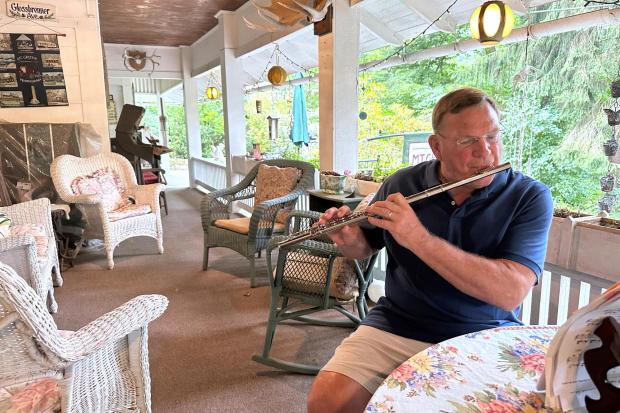 Retired cardiologist Dr. Joe Bering teaches himself flute on the front porch of his cottage in the Campmeeting section of Mount Gretna, Pa., Wednesday, Aug. 6, 2025. (AP Photo/Mark Scolforo)