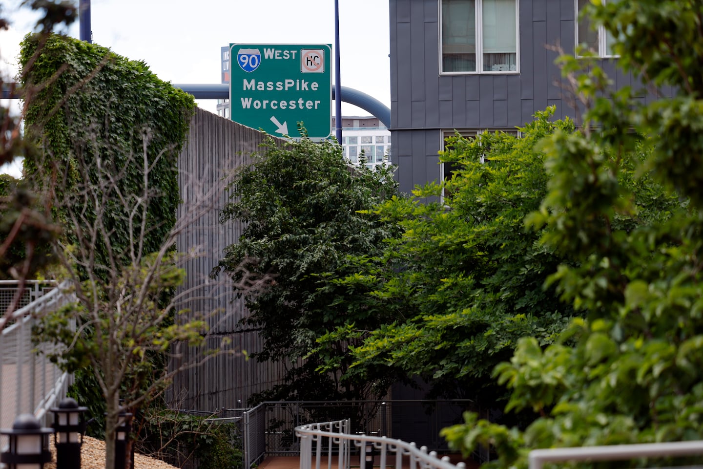 The sign for Interstate 90 can be seen over a cement wall and the new One Greenway Park.