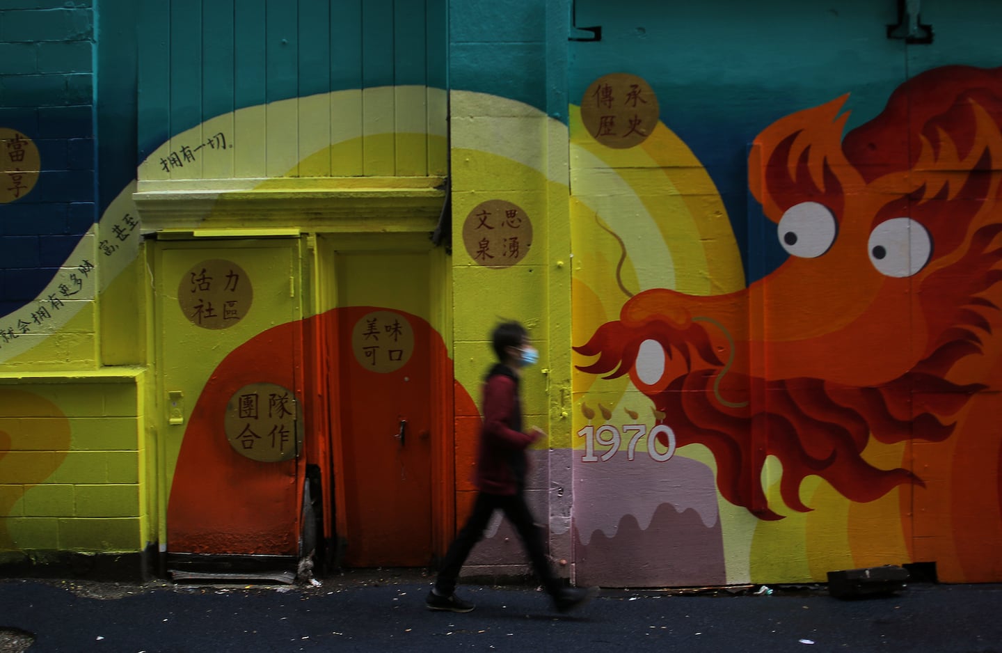 A pedestrian passed the mural “Where We Belong” by Thai artist Ponnapa Prakkamakui and the A-Voyce youth from Asian Community Development Corporation on Oxford Street in Chinatown.