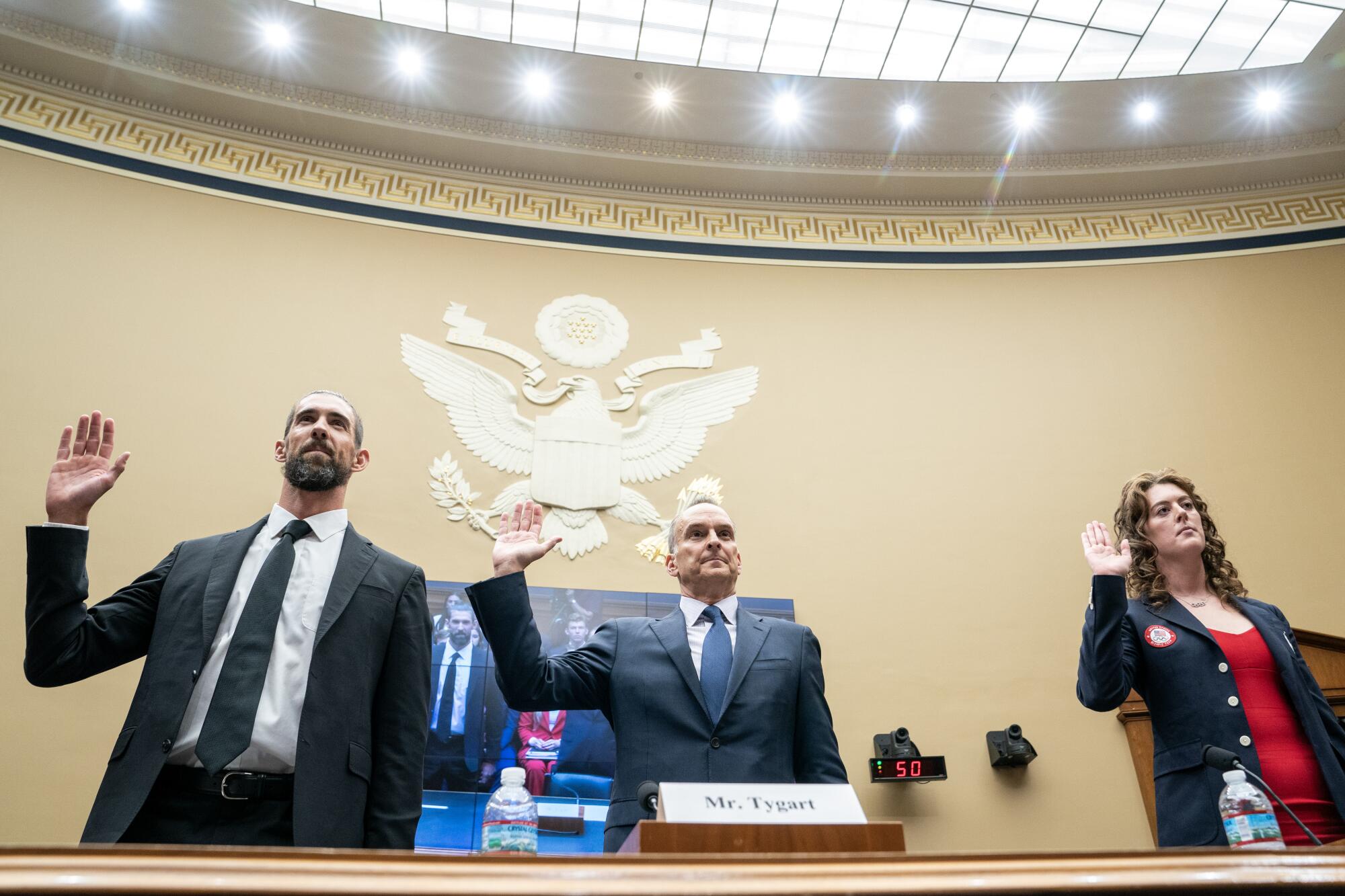 two men and a woman raise their hands to give an oath