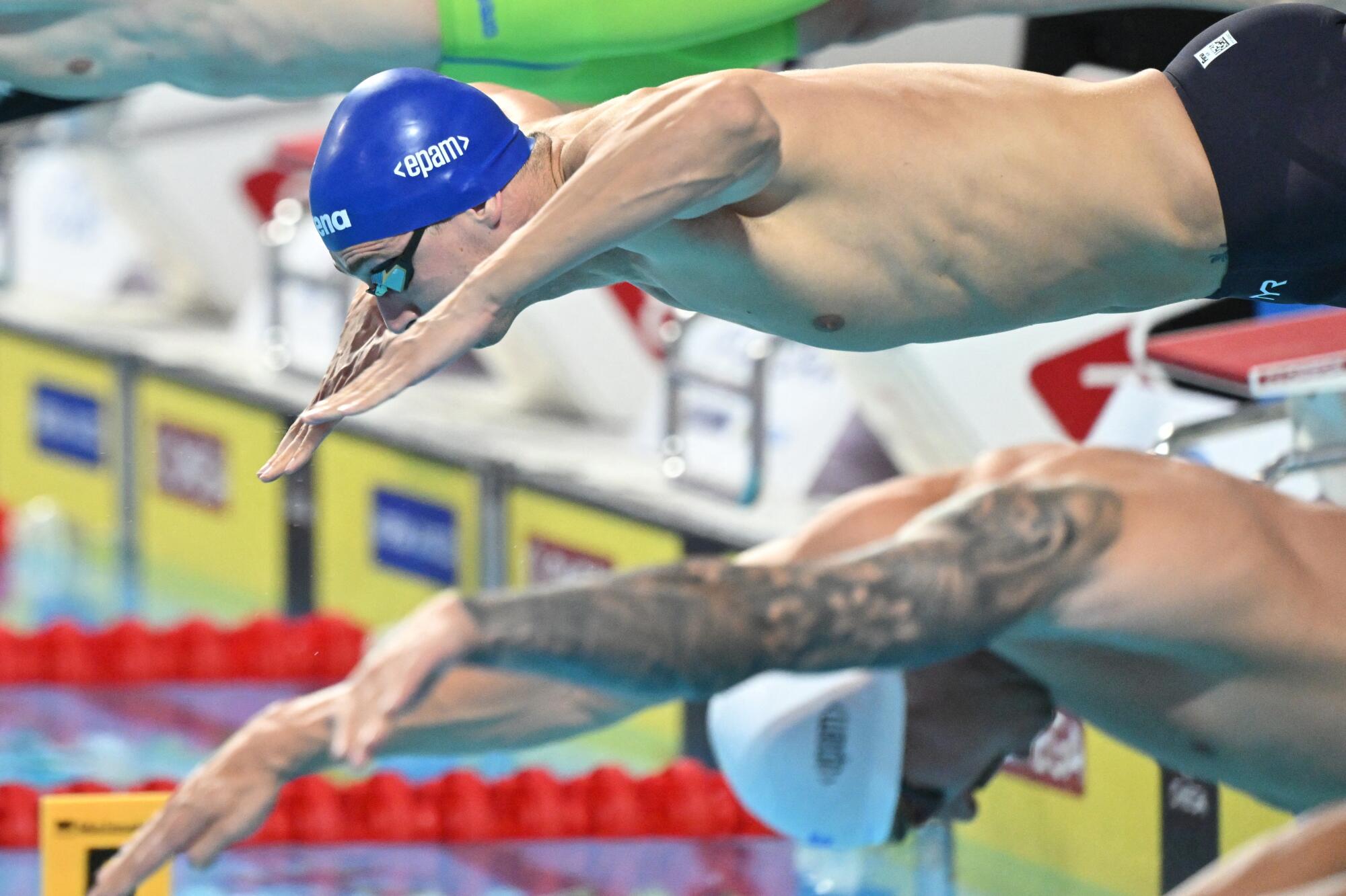 swimmers jump into a pool to compete