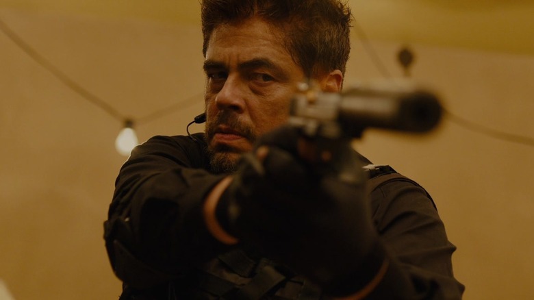 Alejandro Gillick (Benicio del Toro) aiming a silenced pistol in Sicario
