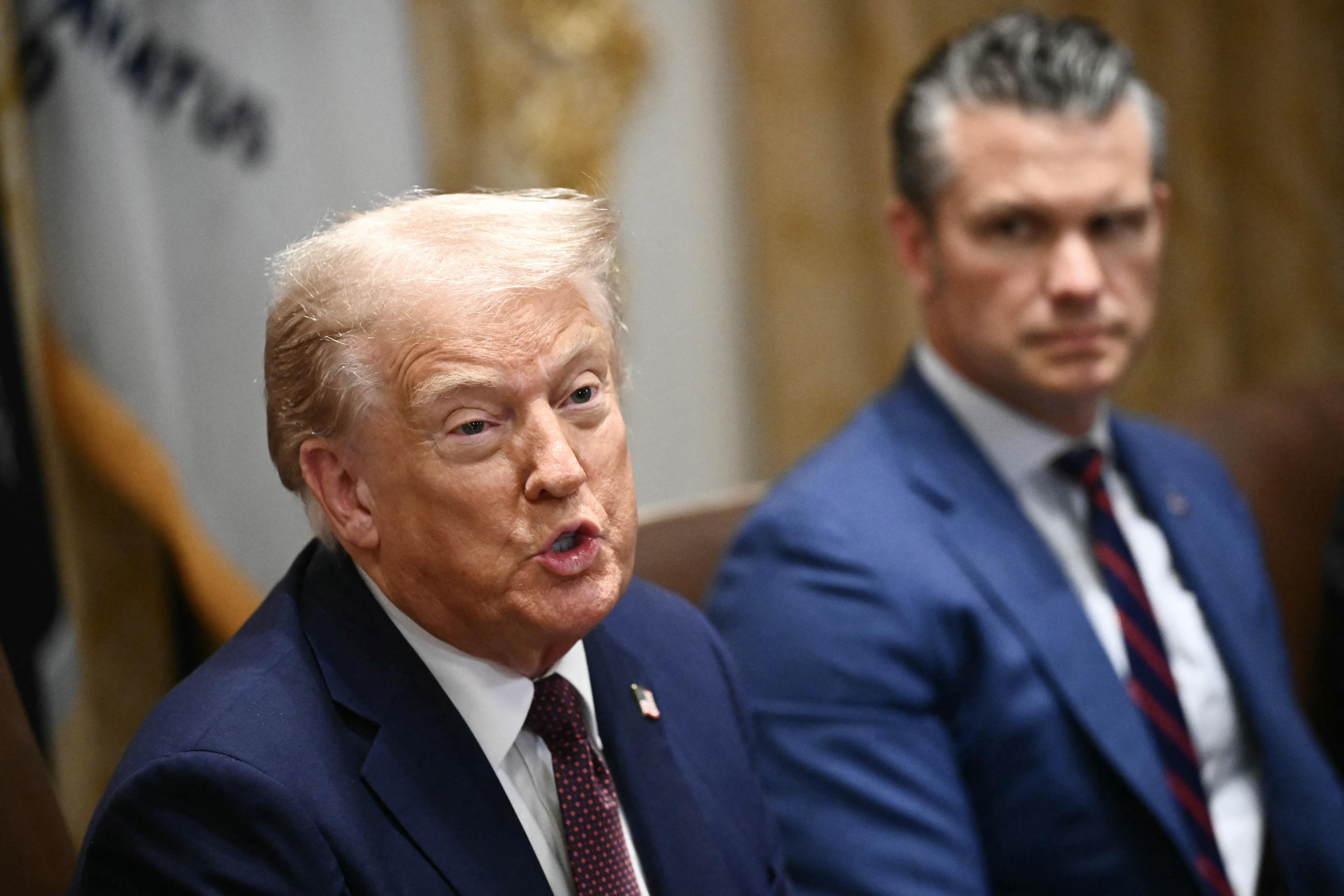 Donald Trump and Pete Hegseth at a conference table.