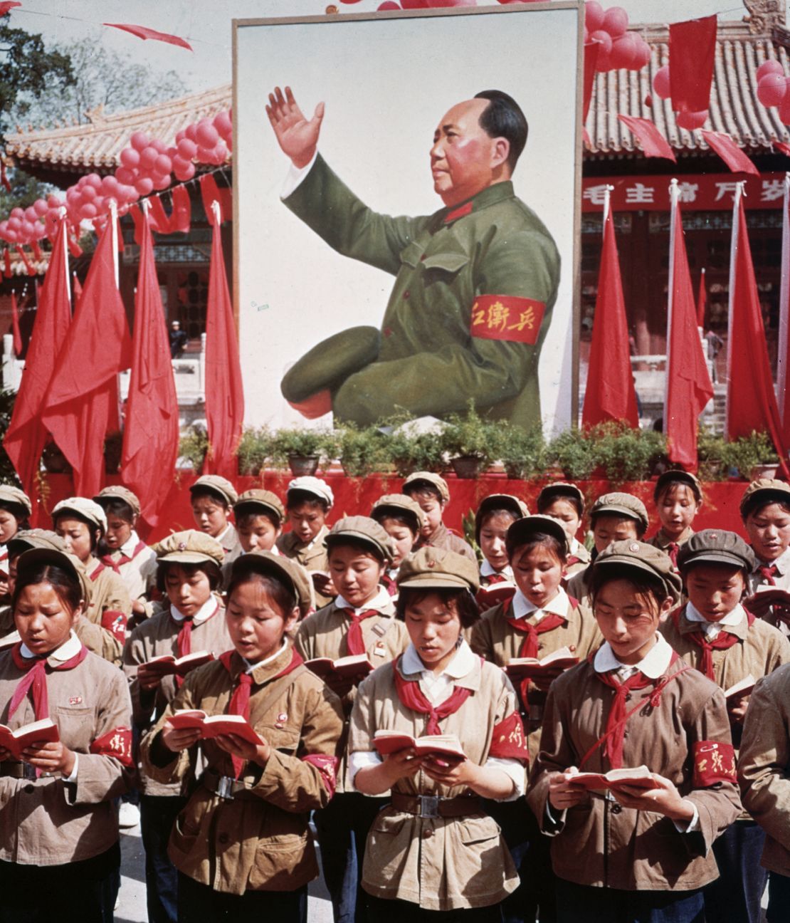 A group of children in uniform stood in front of a giant portrait of Chairman Mao Zedong, reading his 