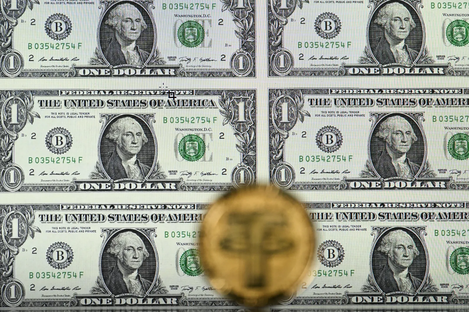 An illustration picture taken in London on May 8, 2022, shows a gold-plated souvenir cryptocurrency Tether (USDT) coin arranged beside a screen displaying U.S. dollar notes.