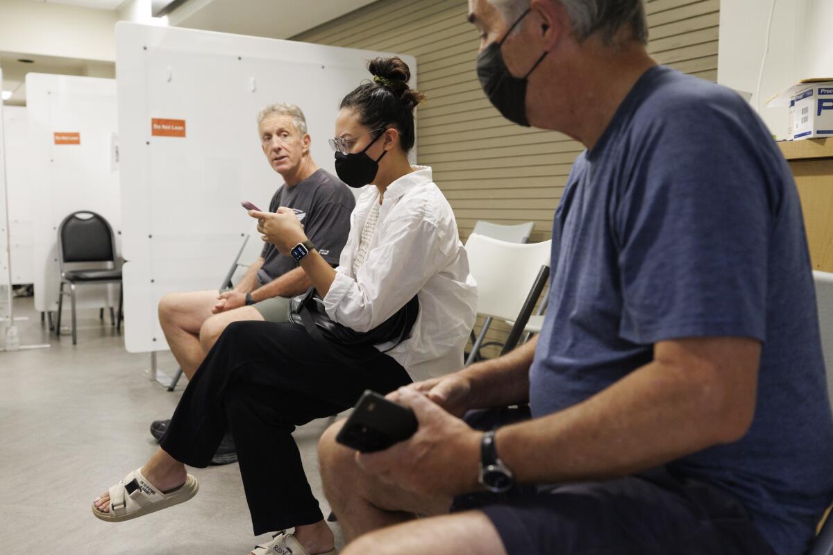 Three patients wait to be vaccinated at a clinic.
