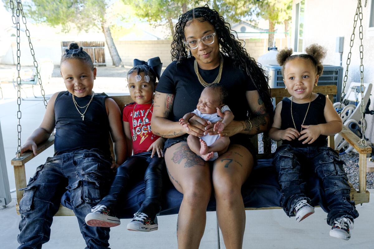 A woman sits with her four children, ages 2 weeks to 6 years old.