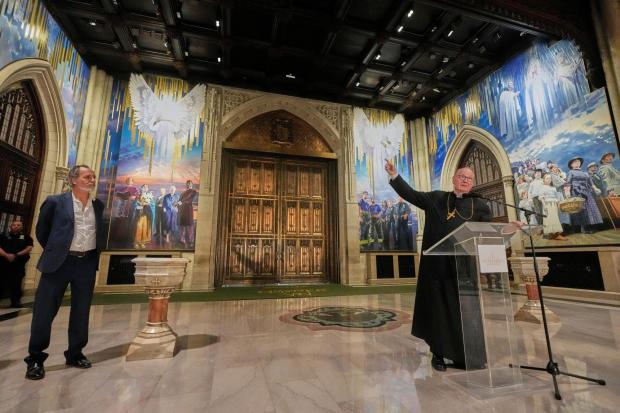 Artist Adam Cvijanovic, left, listens as Cardinal Timothy Dolan speaks during a media preview of the 25-foot-high mural, the largest artwork ever commissioned for St. Patrick