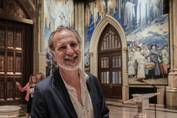 Artist Adam Cvijanovic poses for a photo during the media preview his 25-foot-high mural, the largest artwork ever commissioned for St. Patrick