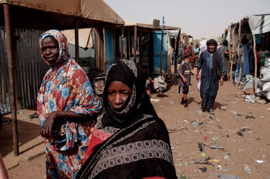 People walk through the weekly market in M