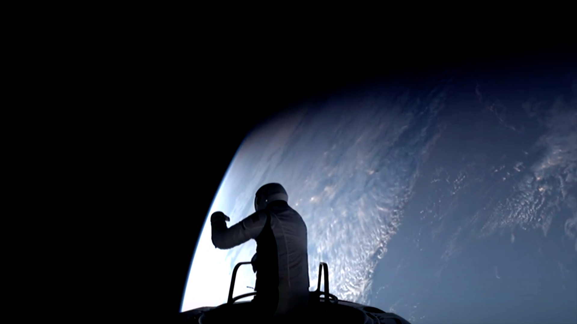 an astronaut with his torso exposed out of a spacecraft hatch, with a blue-and-white earth behind him
