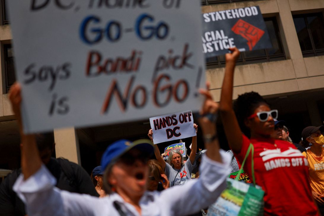 People hold placards protest the appointment of Drug Enforcement Agency head Terry Cole as emergency police commissioner in Washington, DC, on August 15, following President Donald Trump